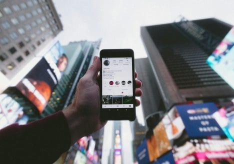 high angle photo of person holding turned on smartphone with tall buildings background